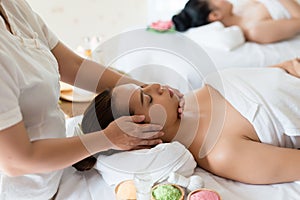 Beautiful Asian girl relaxing receiving facial massage in a spa