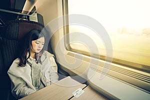 Beautiful asian girl sleeping on the train while listening to music, with copy space, soft warm light tone