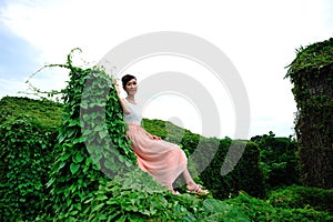 Beautiful Asian girl strolls in the plant wall