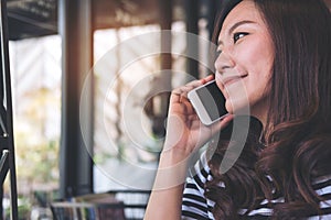 A beautiful Asian girl talking on smart phone with smiley face