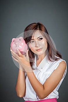 Beautiful Asian girl wonder how much money in piggy bank