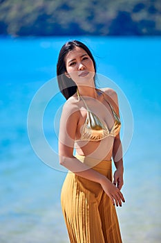 Beautiful asian girl in a yellow pants posing on a beach