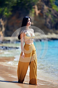 Beautiful asian girl in a yellow pants walking on the beach