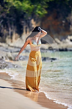 Beautiful asian girl in a yellow pants walking on the beach