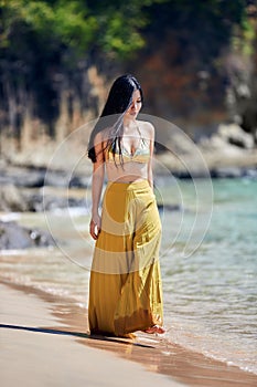 Beautiful asian girl in a yellow pants walking on the beach