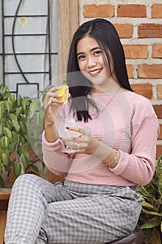 beautiful asian happy woman holding lemon and drinking water glass