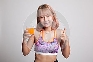 Beautiful Asian healthy girl drinking orange juice thumbs up.
