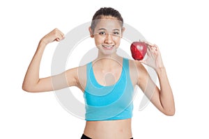 Beautiful Asian healthy girl flexing biceps with red apple