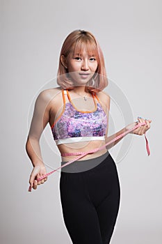 Beautiful Asian healthy girl measuring her waist.