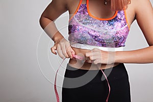 Beautiful Asian healthy girl measuring her waist.