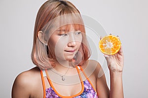 Beautiful Asian healthy girl with orange fruit licks her lips.