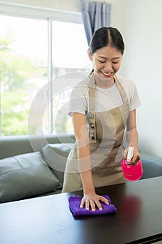 Beautiful Asian housewife doing housework and cleaning the house with an apron, using a vacuum