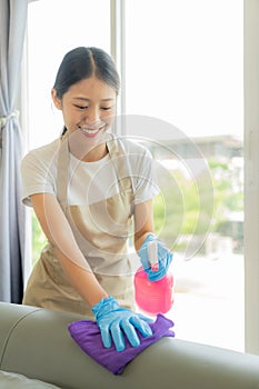 Beautiful Asian housewife doing housework and cleaning the house with an apron, using a vacuum