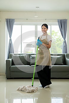 Beautiful Asian housewife doing housework and cleaning the house with an apron, using a vacuum