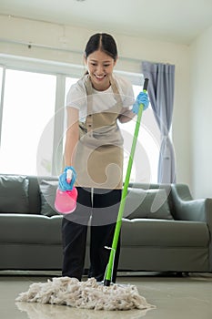 Beautiful Asian housewife doing housework and cleaning the house with an apron, using a vacuum