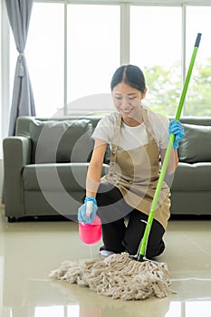Beautiful Asian housewife doing housework and cleaning the house with an apron, using a vacuum