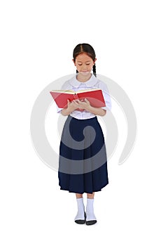 Beautiful Asian little schoolgirl in Thai school uniform standing reading a book isolated on white studio background. Full length