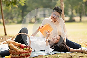 Beautiful Asian mature mother and adult daughter spend a good time together in the park relaxing picnic while the daughter lay on