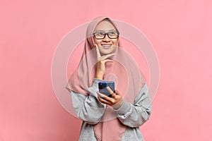 Beautiful Asian Muslim Female smiling and holding smartphone look at a empty space