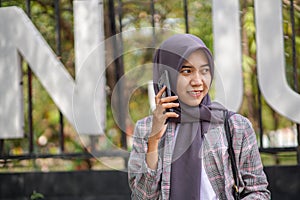 beautiful muslim student calling her friend using smartphone in park