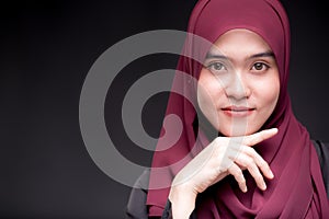 A beautiful Asian Muslim woman is smiling, on isolate black background