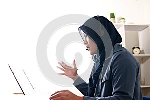 Beautiful Asian muslim woman using headphones speaking her laptop, explaining something. Professional teacher mentor customer