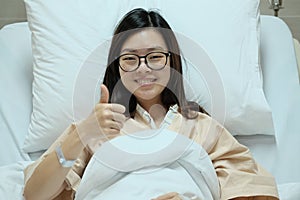 Beautiful Asian patient girl thumbs up and smile on hospital admission bed, medical or health concept