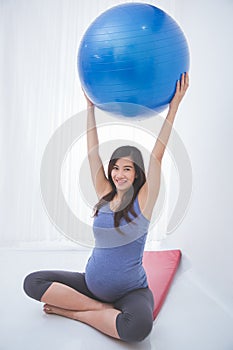 Beautiful asian pregnant woman doing exercise with a yoga ball,