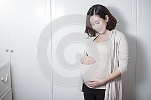 Beautiful asian pregnant woman expecting  baby and touching her belly