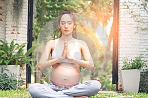 Beautiful Asian pregnant woman relaxing in the park. Right choice for your baby. Pregnant woman having meditation in nature