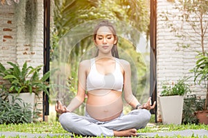 Beautiful Asian pregnant woman relaxing in the park. Right choice for your baby. Pregnant woman having meditation in nature