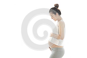 Beautiful asian pregnant woman smiling and touching her belly on the white background. Pregnancy healthy motherhood concept.