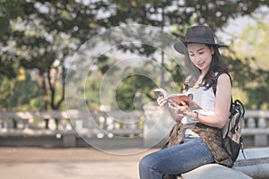 Beautiful asian solo tourist woman reading the travel guide book searching for for tourists sightseeing spot