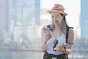 Beautiful asian solo tourist woman smiling and looking at mobile phone for searching tourists sightseeing spot