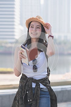Beautiful asian solo tourist woman smiling and searching for tourists sightseeing spot.
