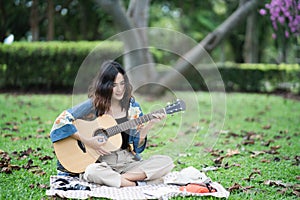 Beautiful Asian student picnic in the park and thinking Composing song