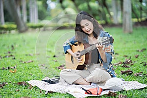 Beautiful Asian student picnic in the park and thinking Composing song