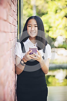 Beautiful asian teenager toothy smiling face using smarphone in