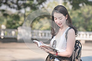 Beautiful asian tourist woman reading the travel guide book searching for for tourists sightseeing spot