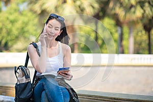 Beautiful asian tourist woman reading the travel guide book searching for for tourists sightseeing spot.