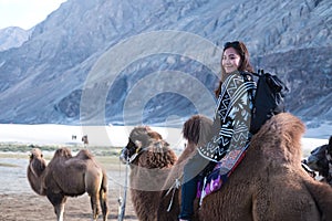 A beautiful Asian tourist woman riding camel in the Hunder desert