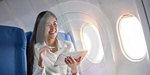 Beautiful asian travel woman watching movie on digital tablet in airplane