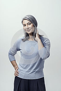 Beautiful Asian with white hair smiling standing near the wall