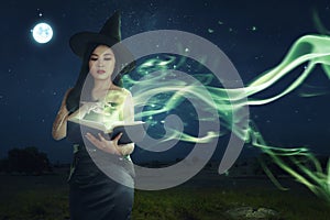 Beautiful asian witch woman learning the magic spell from book