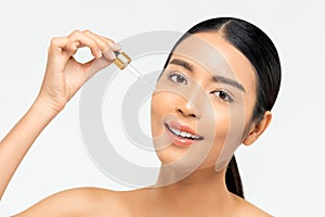 Beautiful Asian woman applying anti aging moisturizing serum on her face