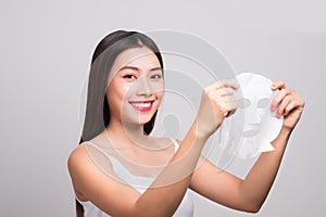 Beautiful asian woman applying paper sheet mask on her face whit