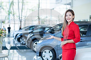 Beautiful Asian woman or car salesman Stand holding a new car remote key in the showroom, Cars For Sale