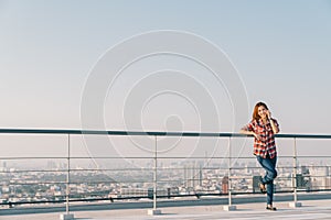 Beautiful Asian woman or college student using mobile phone call at rooftop alone or lonely, downtown cityscape background