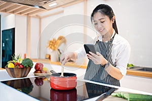 Beautiful Asian woman cooking in the kitchen She is looking at recipes on her smartphone