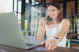 Beautiful asian woman with digital laptop computer happy and relax at coffee shop.